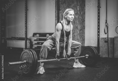 Muscular Woman performs deadlift with weight in modern functional gym