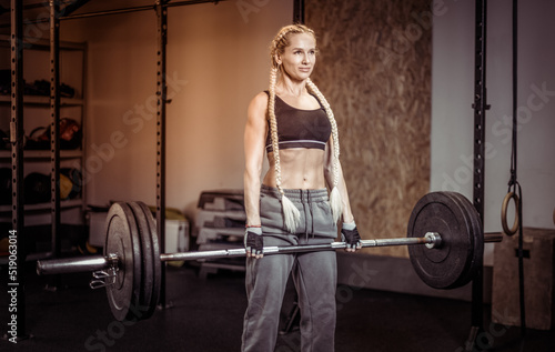 Muscular Woman performs deadlift with weight in modern functional gym