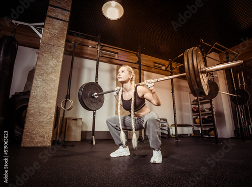 Wallpaper Mural Young fit woman doing squats with heavy barbell on her shoulders in modern gym