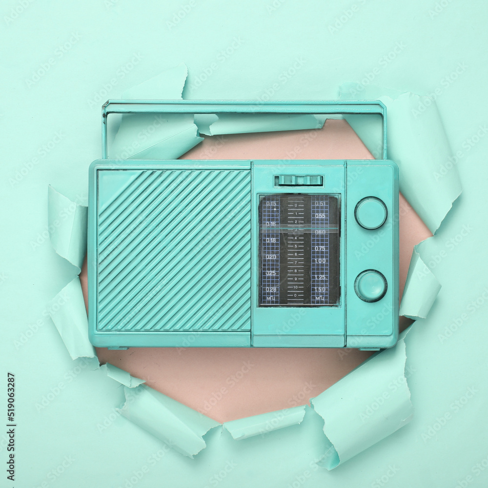 Creative music layout. Blue analog radio receiver through the torn hole of pink paper. Minimalism. Concept art. Flat lay. Top view. Creative music layout. Blue analog radio receiver through the torn hole of pink paper. Minimalism. Concept art. Flat lay. Top view.