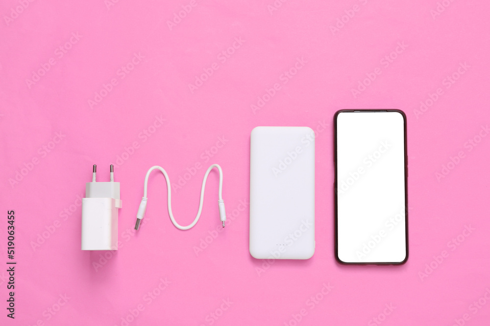 Smartphone, External portable battery (power bank) with charging device on pink background. Top view. Flat lay Smartphone, External portable battery (power bank) with charging device on pink background. Top view. Flat lay