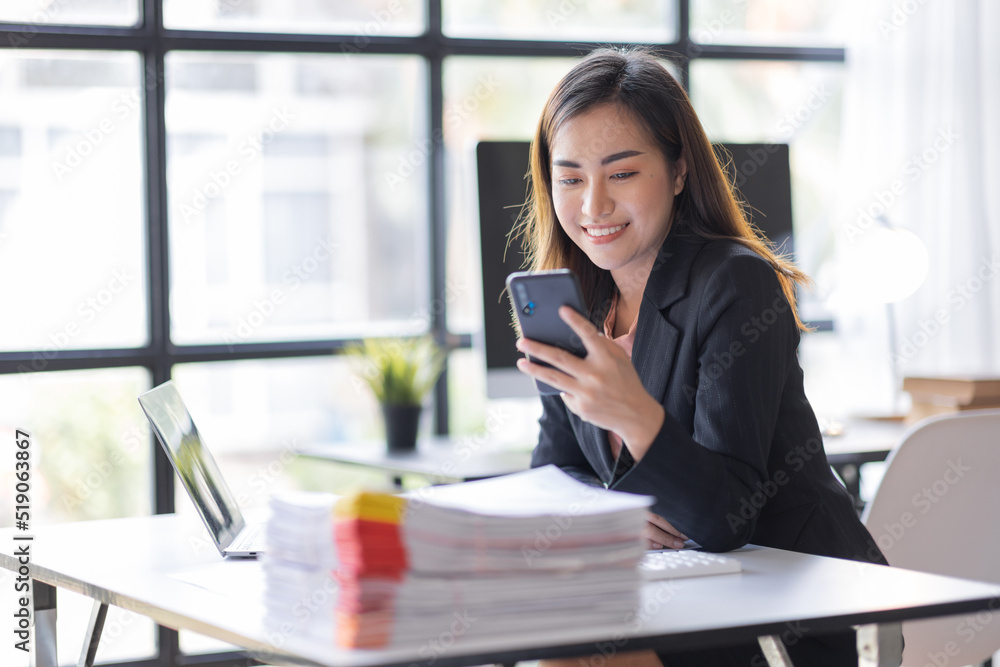 Business asian woman using mobile phone during checking an email or social media on internet working on laptop accounting financial concept. Business asian woman using mobile phone during checking an email or social media on internet working on laptop accounting financial concept.