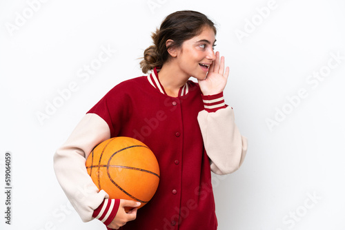 Young basketball player woman isolated on white background shouting with mouth wide open to the side © luismolinero