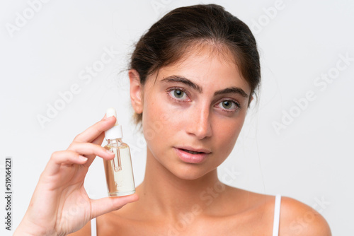 Young Pretty caucasian woman isolated on white background holding a serum. Close up portrait