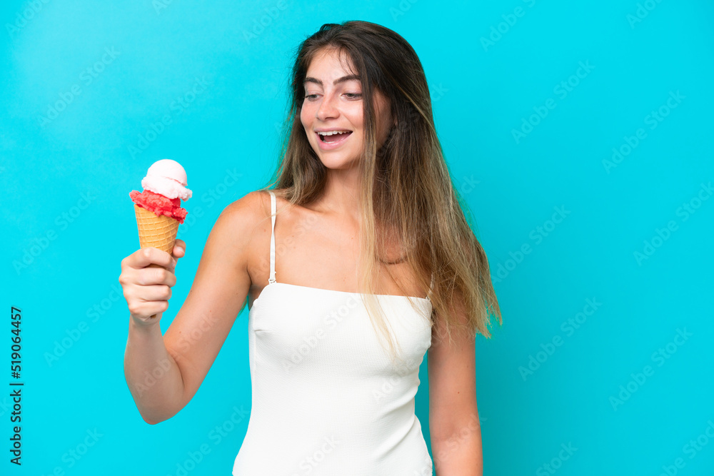 Young woman in swimsuit holding an ice cream isolated on blue background with happy expression Young woman in swimsuit holding an ice cream isolated on blue background with happy expression