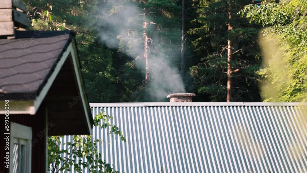 smoke wafts out of a chimney in a mountain resort. A bit of green wood makes for a bit of extra smoke in this cinematic shot. Tall blades of seeding grass move into the foreground smoke wafts out of a chimney in a mountain resort. A bit of green wood makes for a bit of extra smoke in this cinematic shot. Tall blades of seeding grass move into the foreground