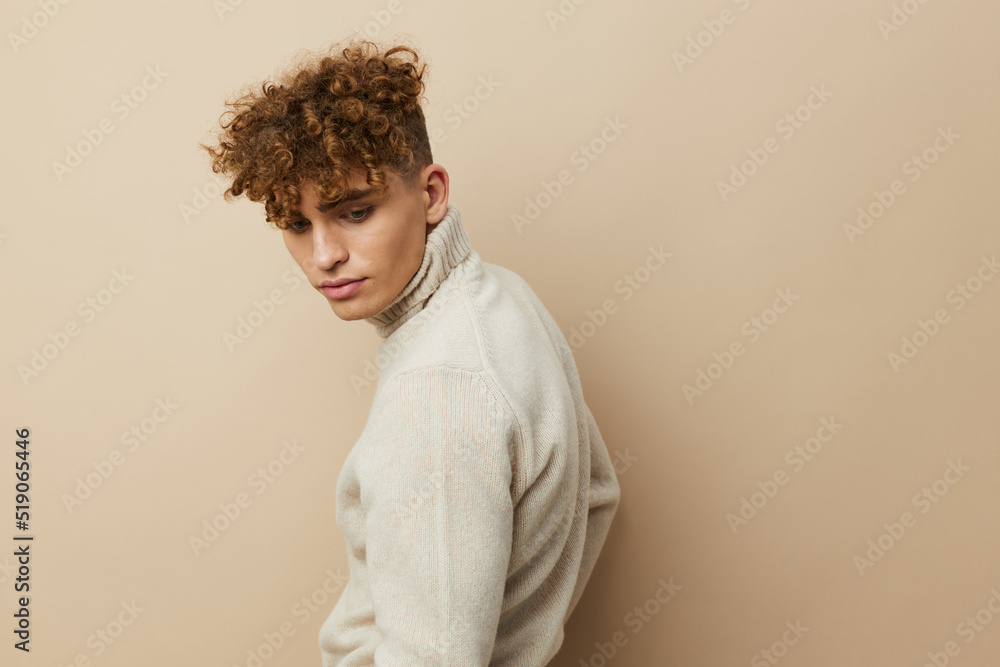 a handsome, attractive man stands on a beige background in stylish clothes and turns his back to face the camera a handsome, attractive man stands on a beige background in stylish clothes and turns his back to face the camera