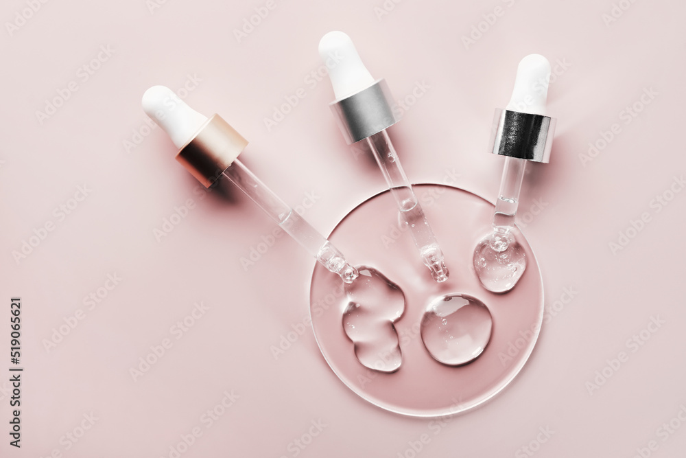 Three pipettes with different samples of gels cosmetic products in petri dish on pink background Three pipettes with different samples of gels cosmetic products in petri dish on pink background
