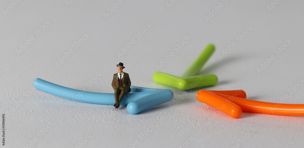 A miniature man sitting on an arrow. Miniature and business concept.
A miniature man sitting on an arrow. Miniature and business concept.