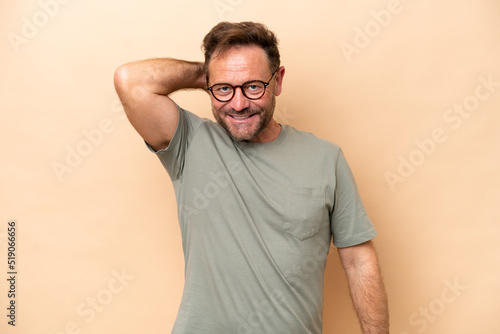 Middle age caucasian man isolated on beige background laughing