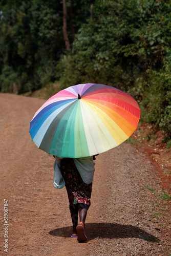 Woman walking on a country road and carrying an umbrella