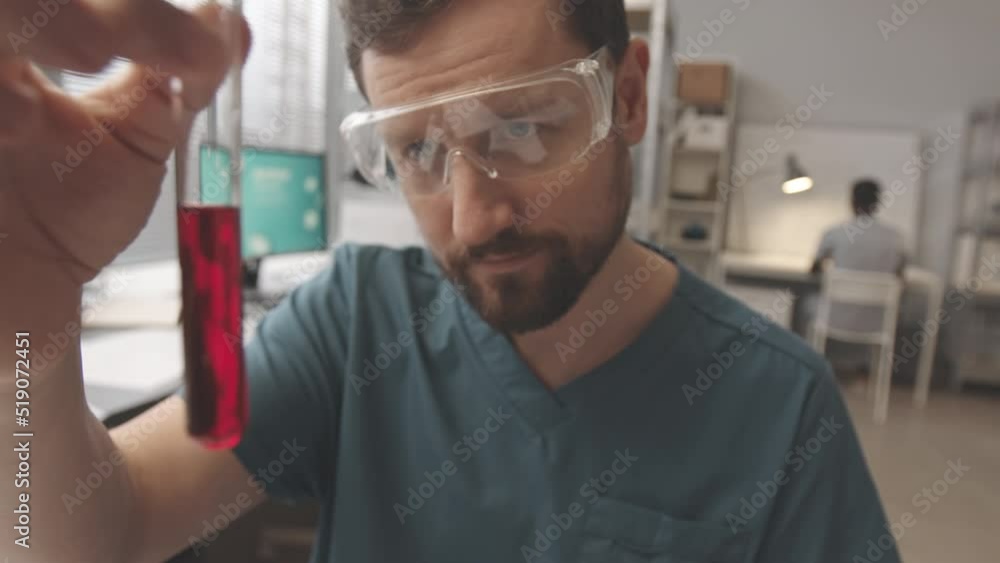 POV of unrecognizable chemist asking colleagues to examine red liquid substance in glass test tube, working together in modern laboratory POV of unrecognizable chemist asking colleagues to examine red liquid substance in glass test tube, working together in modern laboratory