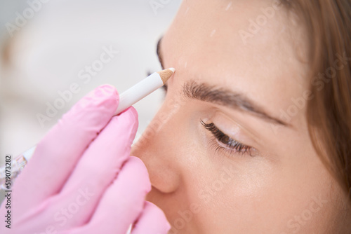 Lady between eyebrows is schematically marked with pencil for procedure