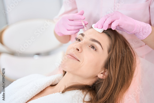 Cosmetologist doing injection procedure on face of a young woman