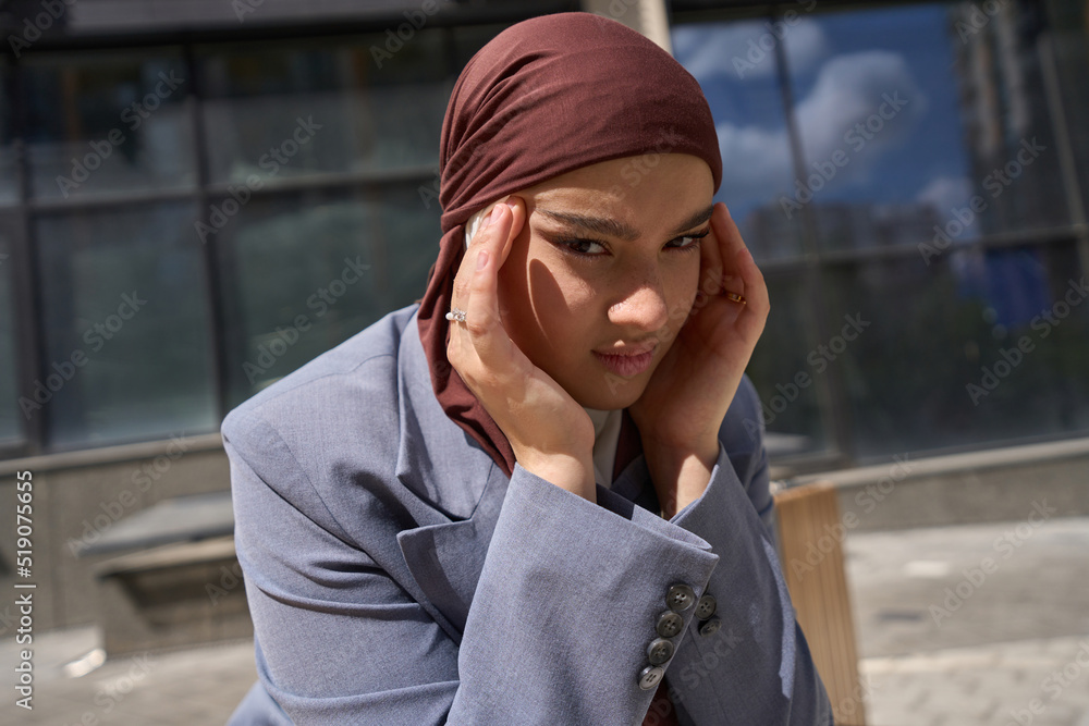 Arab woman in a jacket holding her head