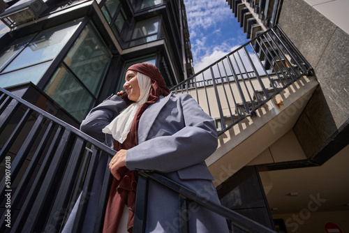 Wallpaper Mural Arab woman stands on ladder against the background of high-rise building and sky Torontodigital.ca