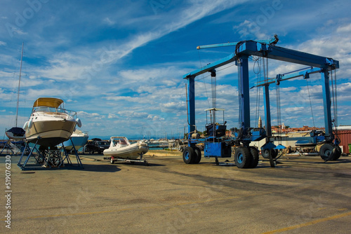 A mobile suspended boat lift or hoist, and a small leisure boat being repaired on a boat cradle at Izola marina on Slovenia's Adriatic coast 