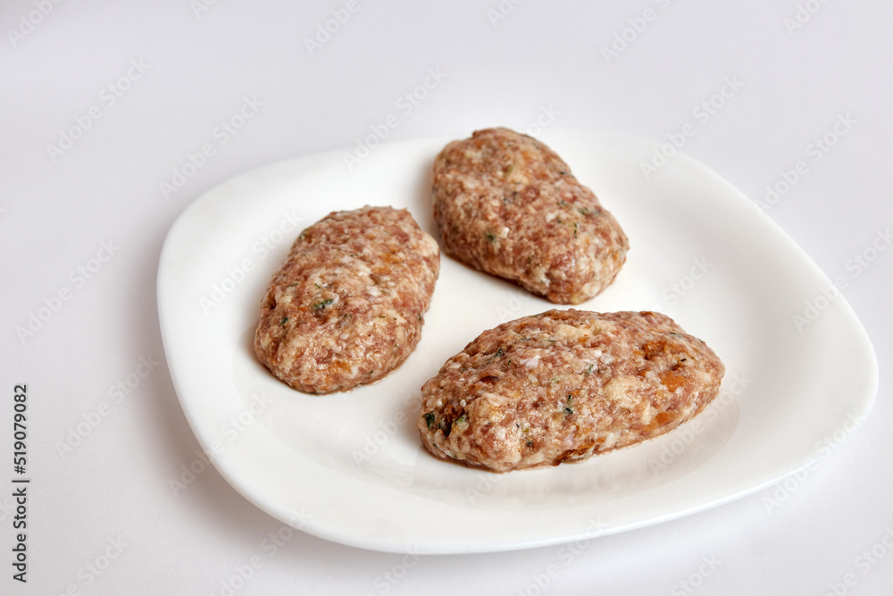 Raw cutlets from minced meat on a white plate. Raw cutlets from minced meat on a white plate.