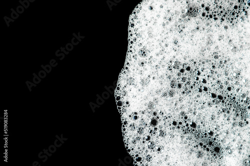 Texture of white foam on a black background. Cleansing mousse for the face or shaving foam or washing powder. Isolated on a black background. © mitand73