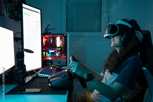 Man wearing VR glasses using steering wheel sitting at home photo