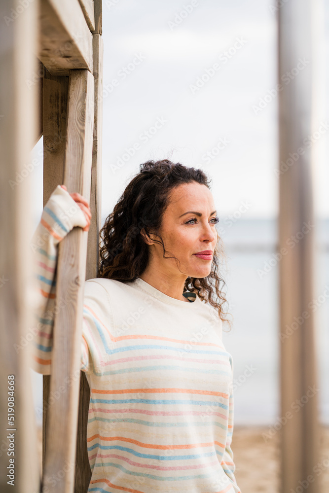 Thoughtful woman standing by wooden structure Thoughtful woman standing by wooden structure