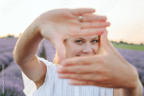 Happy woman looking through finger frame photo