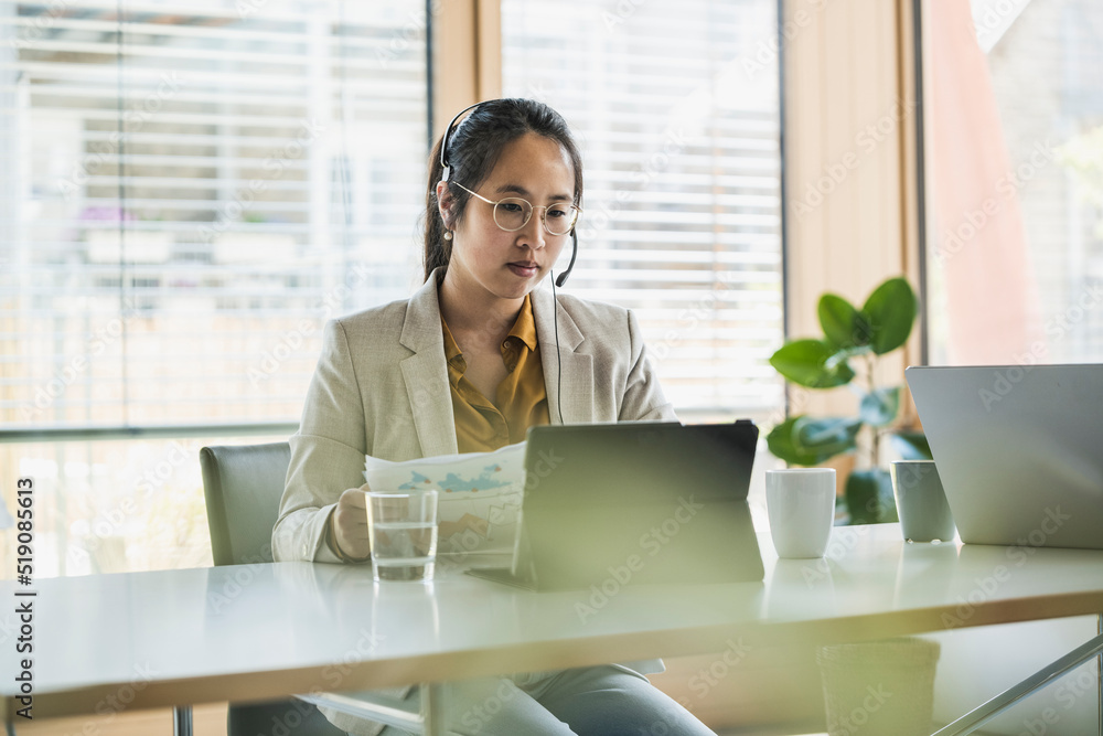 Businesswoman with headset working on tablet PC in office Businesswoman with headset working on tablet PC in office