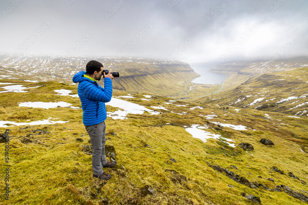 Male hiker photographing Kaldbaksfjordur fjord
