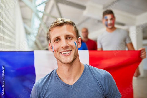 Smiling man with French Flag painted on face at sports event in stadium photo