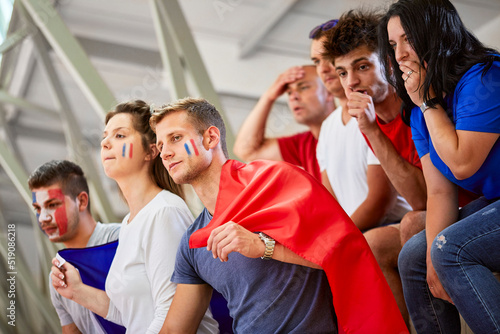 Curious fans with French Flag watching sports event at stadium photo