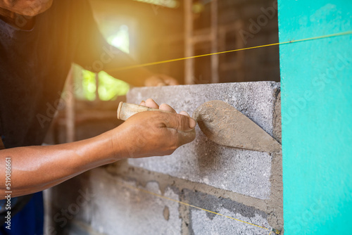 Close-up shot of a bricklayer building a house or walls with mortar and bricks