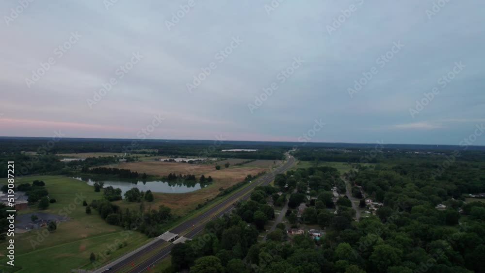 An aerial shot of a beautiful nature at sunset. A vacant green area is seen along with a road going through the field An aerial shot of a beautiful nature at sunset. A vacant green area is seen along with a road going through the field