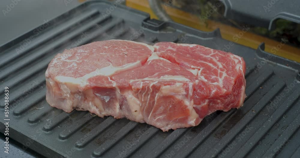 Juicy beef steak with rosemary is cooked on an electric grill Juicy beef steak with rosemary is cooked on an electric grill