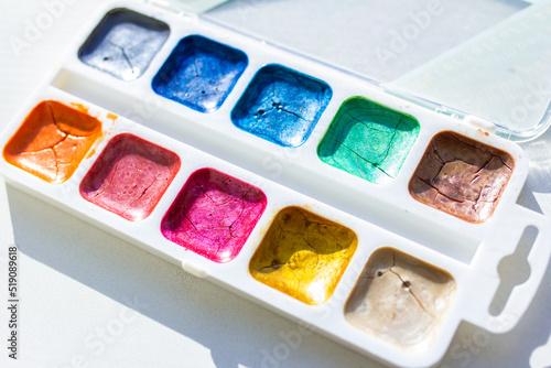 Palette with bright cracked glitter paints, palette with multicolored paints, selective focus