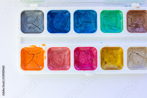 Palette with old cracked multicolored paints with sequins, art background, selective focus