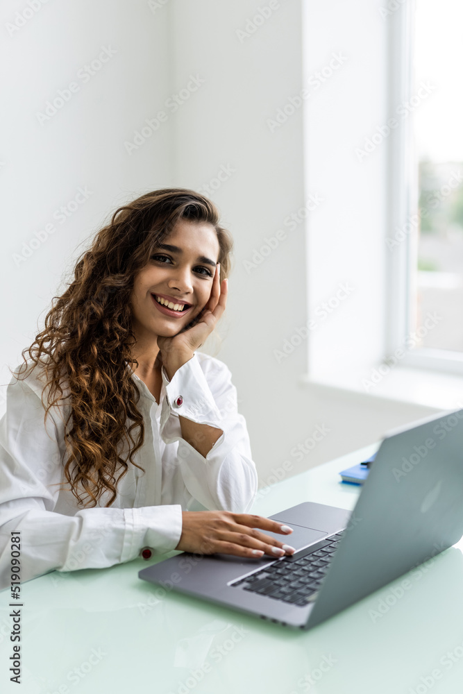 Young beautiful joyful woman smiling while working with laptop in office Young beautiful joyful woman smiling while working with laptop in office