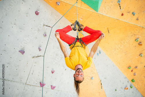 Quadro su tela A man hangs upside down in a lotus position on a climbing wall