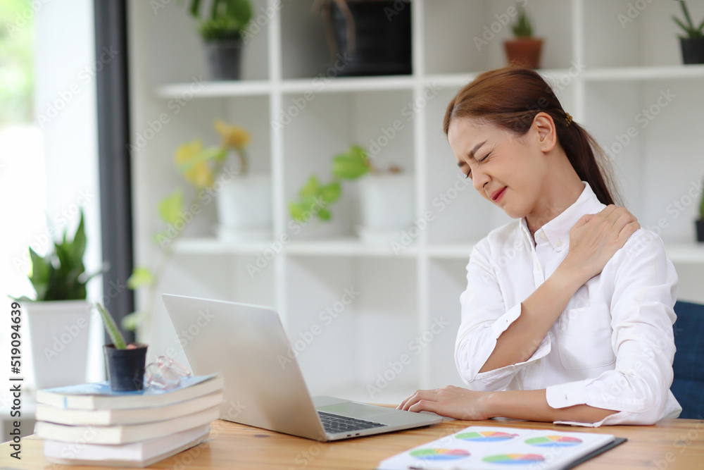 Asian woman touching massaging stiff neck to relieve pain in muscles after sedentary computer work in incorrect posture. Asian woman touching massaging stiff neck to relieve pain in muscles after sedentary computer work in incorrect posture.
