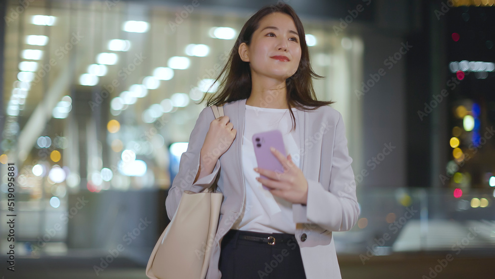 会社帰りにスマホを見るビジネスウーマン 会社帰りにスマホを見るビジネスウーマン