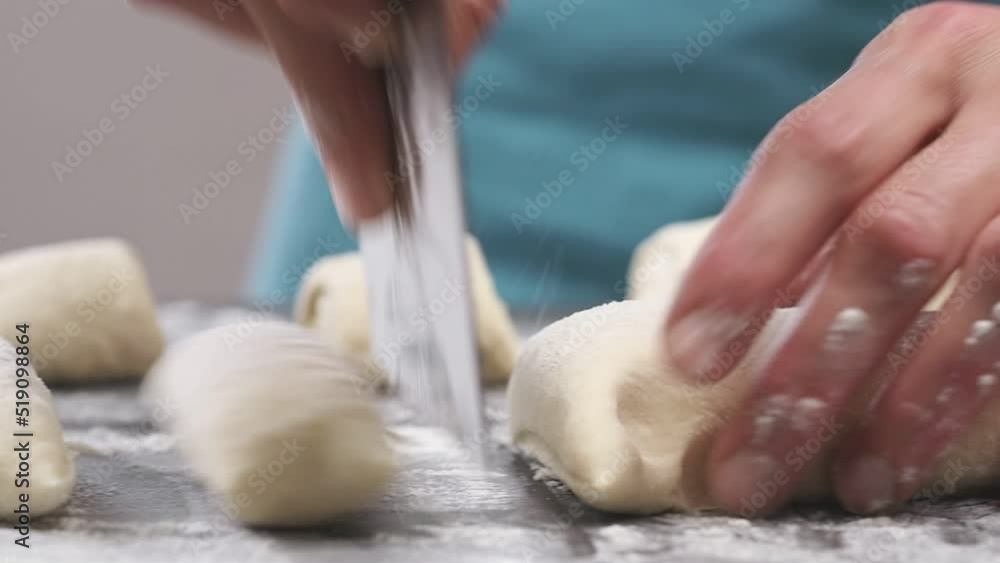 Cutting dough for bread rolls on a table.
Cutting dough for bread rolls on a table.