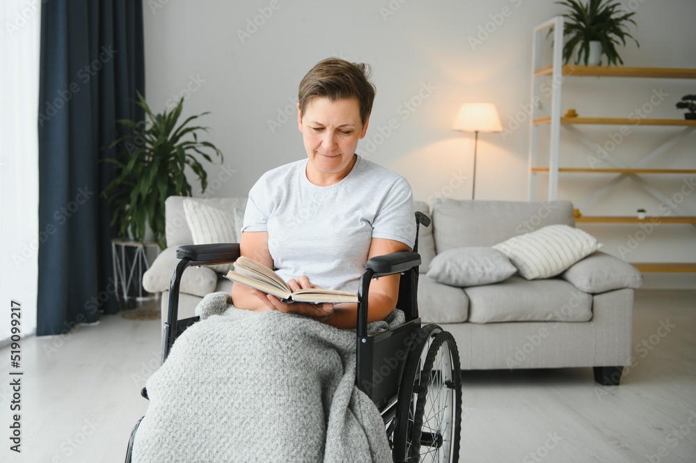 Shot of a senior woman sitting in a wheelchair and reading book at home Shot of a senior woman sitting in a wheelchair and reading book at home