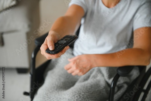 woman in wheelchair uses a tv remote control.