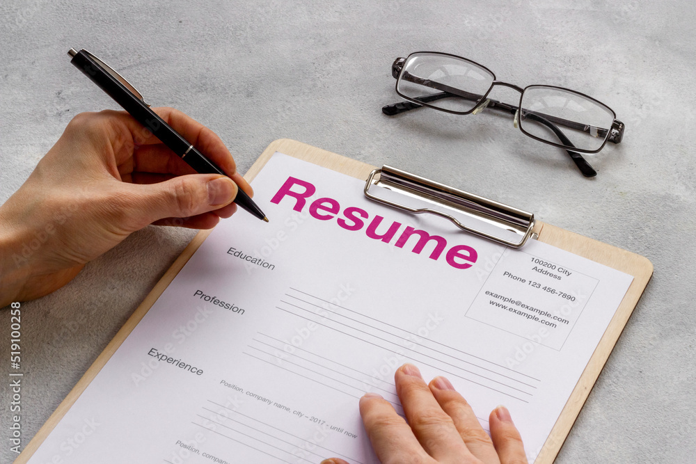 Hands with resume application form on office table. Find new job concept Hands with resume application form on office table. Find new job concept