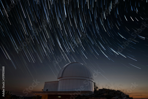 Astronomical observatory under star trails sky at night photo