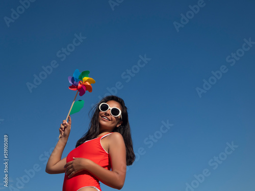 Woman with pinwheel against blue sky © Juan