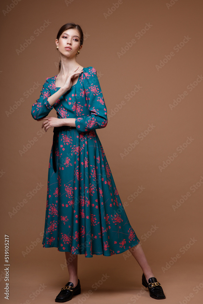 Fashion photo of a beautiful elegant young asian woman in a pretty blue ocean color dress with a floral pattern posing over brown coffee background. Studio Shot. Portrait Fashion photo of a beautiful elegant young asian woman in a pretty blue ocean color dress with a floral pattern posing over brown coffee background. Studio Shot. Portrait