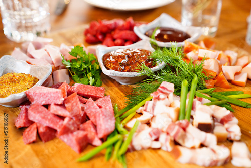 wooden dish with meat cuts, herbs, spices and sauce. 