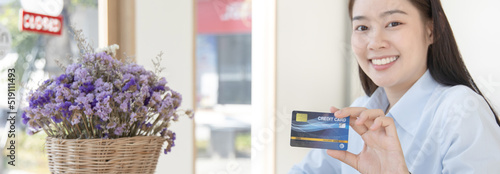 Young Asian business woman holding a credit card and smiling happily, Credit card purchases, Technology era concept.