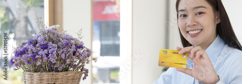 Young Asian business woman holding a credit card and smiling happily, Credit card purchases, Technology era concept.
