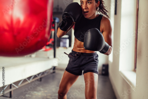 Sporty young woman training with a red punching bag in a boxing gym © Jacob Lund
